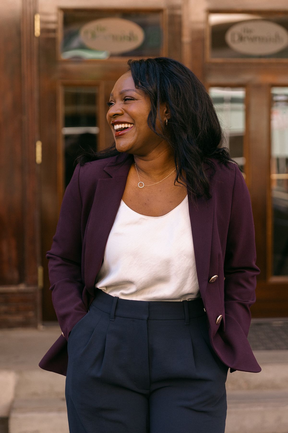 Rozella laughing and looking off to the side in a plum blazer